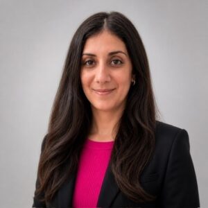 Image of Stacy Gordon, LCSW with long dark hair, a black suit jacket with a vibrant pink blouse and gray background.